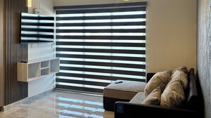 A modern living room with a flat-screen TV, a sofa, and a coffee table. There are two pendant lights and a ceiling light. - Apartment with comfort, security and exclusivity guaranteed! (Mazatlán)