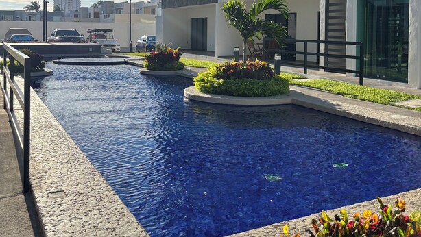 A modern building with a pool and outdoor seating area. - Apartment with comfort, security and exclusivity guaranteed! (Mazatlán)