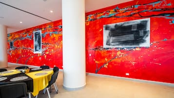 A dining area with tables set for a meal, a large column, and vibrant abstract wall art.