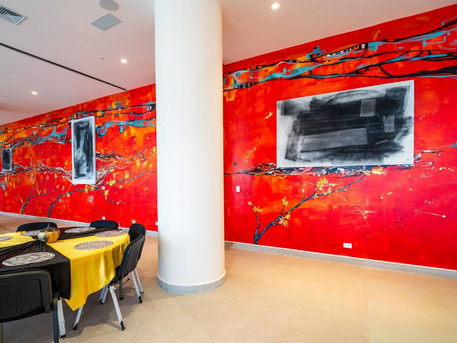 A dining area with tables set for a meal, a large column, and vibrant abstract wall art.