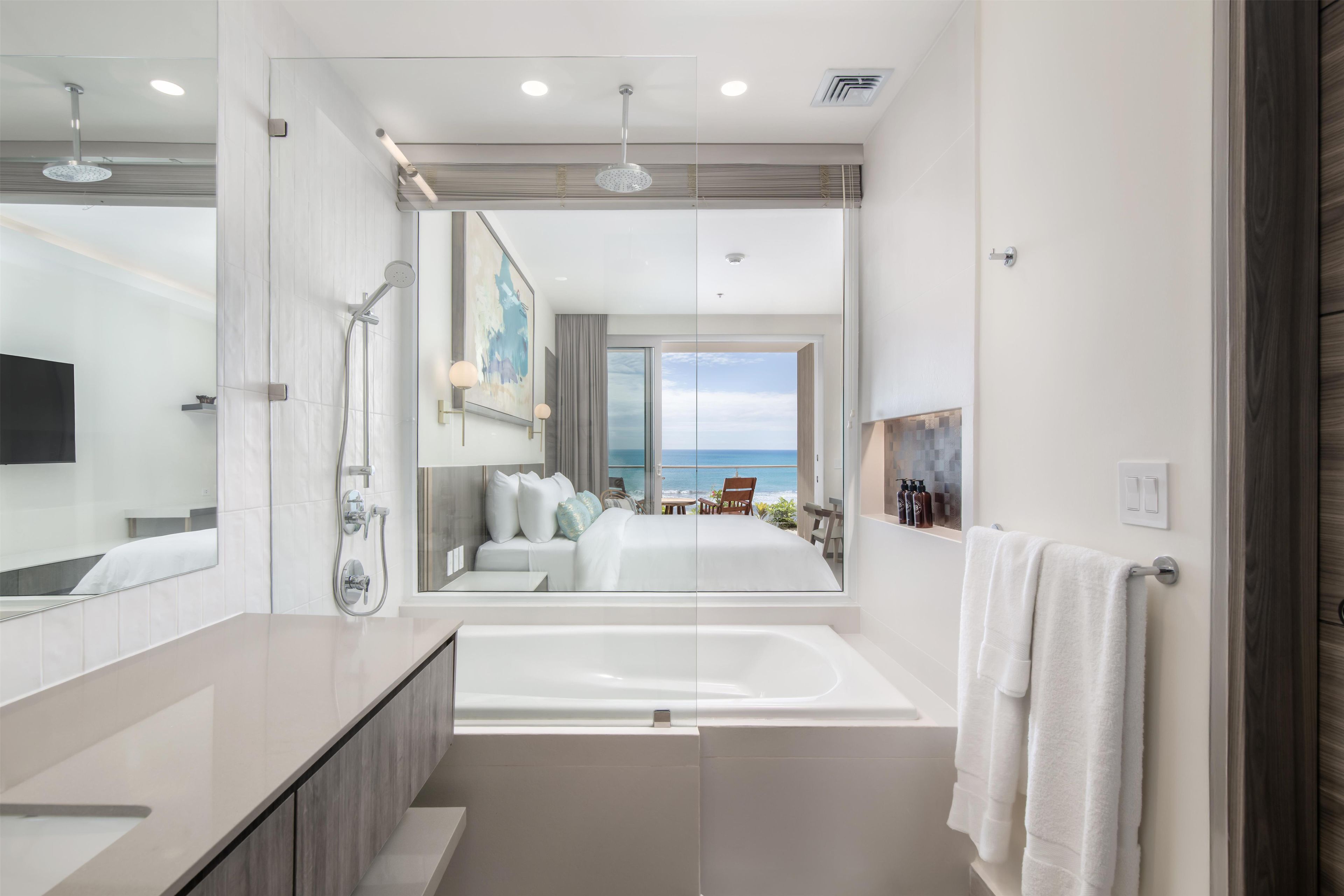 A modern bathroom with a large bathtub, a shower, and a mirror.