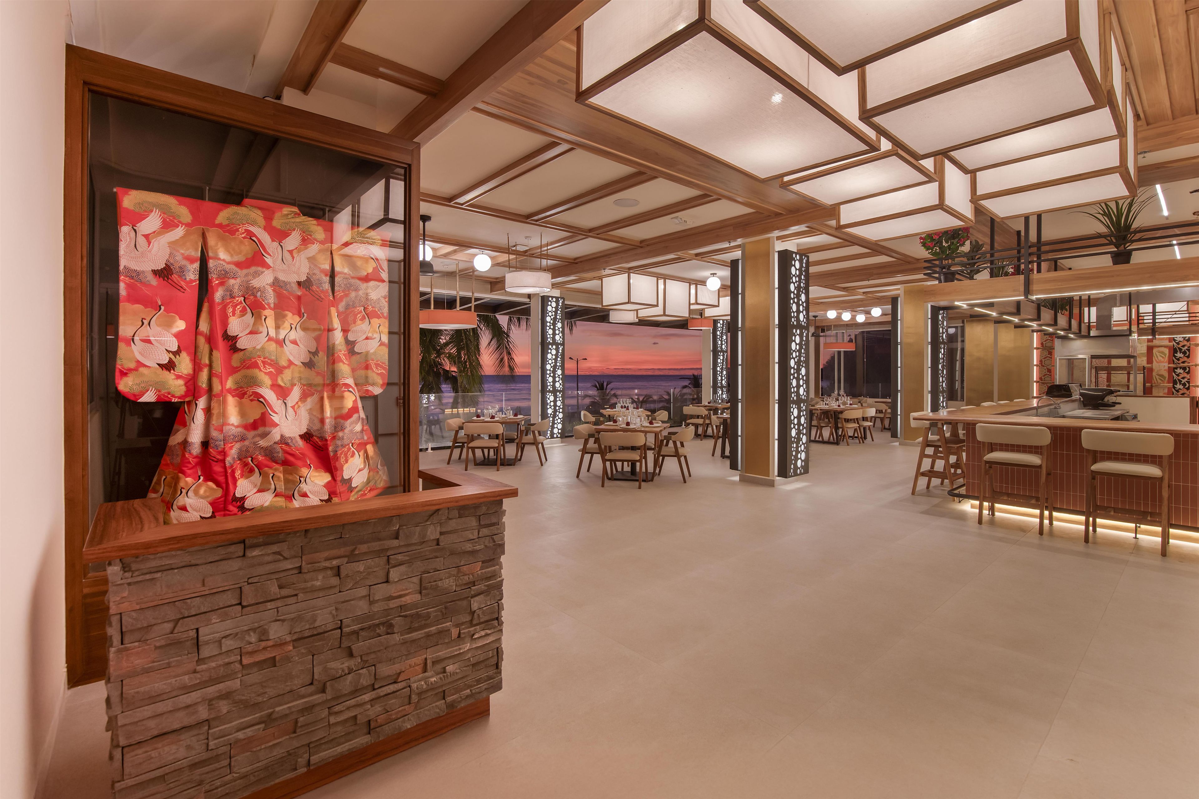 Ein großzügiges Restaurant mit einer Steintheke, Holzbalkendecke und Blick auf den Sonnenuntergang.