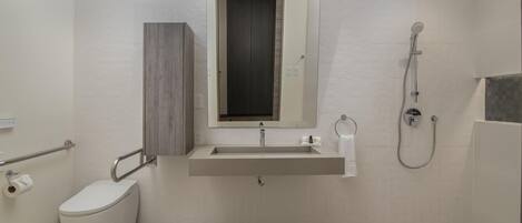 A bathroom with a toilet, sink, mirror, and shower.