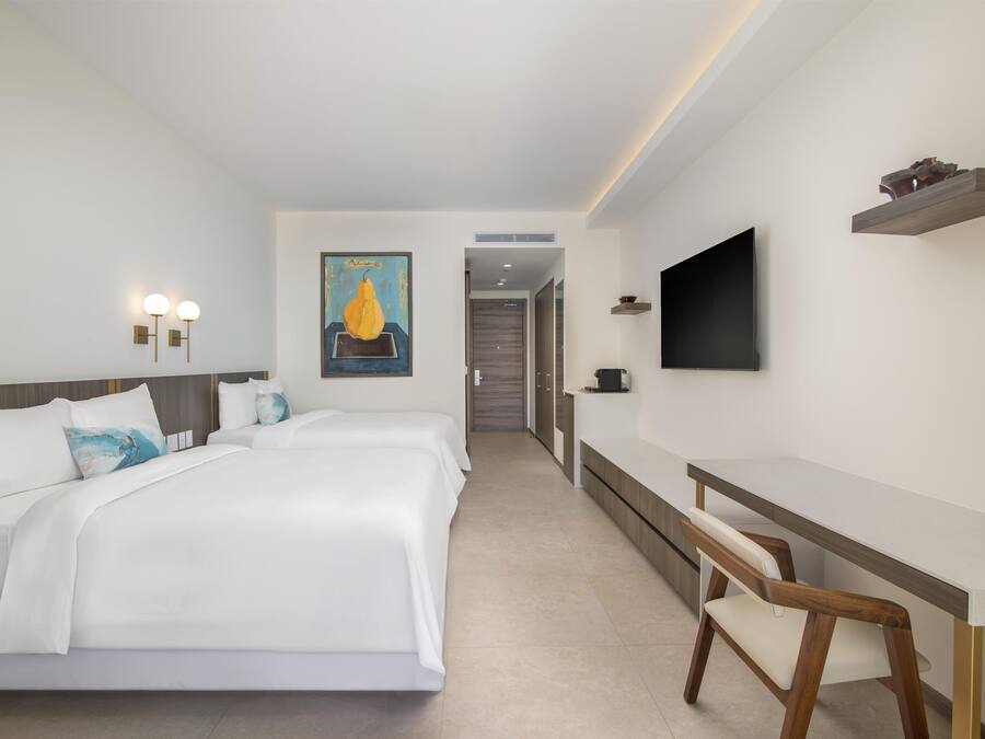 Habitació d'hotel amb un llit gran, una taula de treball, una cadira, un televisor i un quadre a la paret.