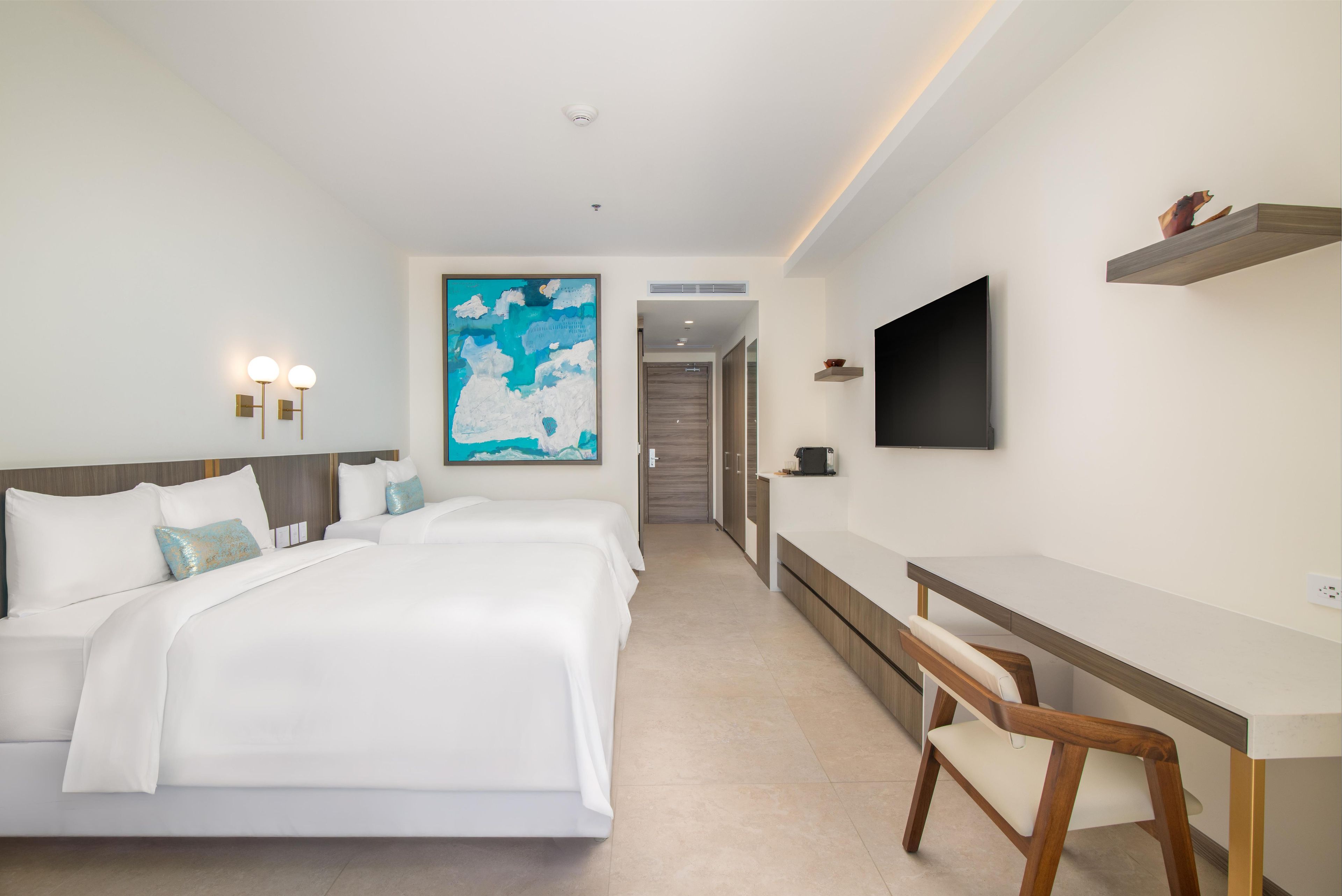 Ein Hotelzimmer mit einem großen Bett, einem Schreibtisch, einem Sessel, einem Flachbildfernseher und einem Bild an der Wand.