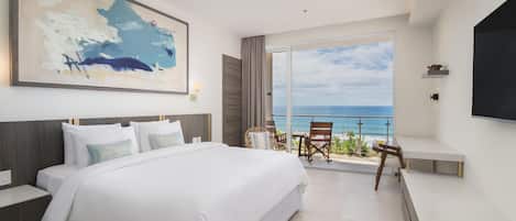 Quarto de hotel com uma cama grande, uma televisão, uma varanda com vista para o oceano e um quadro na parede.