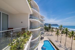 Un hotel de varios pisos con balcones, piscina y vista a la playa.