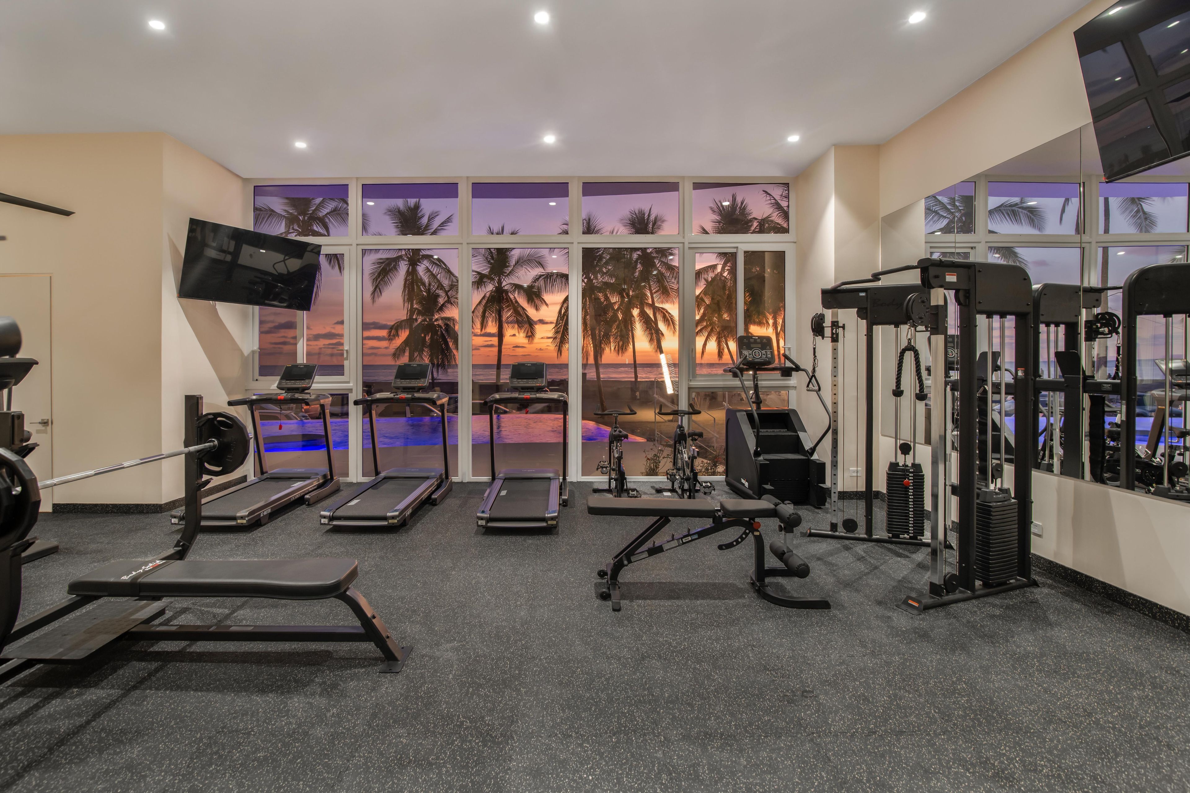 Un gimnasio con cintas de correr, máquinas de pesas y una televisión.