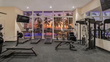 Un gimnasio con cintas de correr, máquinas de pesas y una televisión.