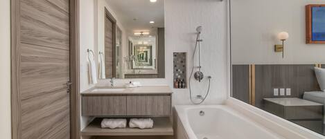 Une salle de bain moderne dotée d’une grande baignoire, d’un meuble-lavabo avec miroir et d’un espace douche.