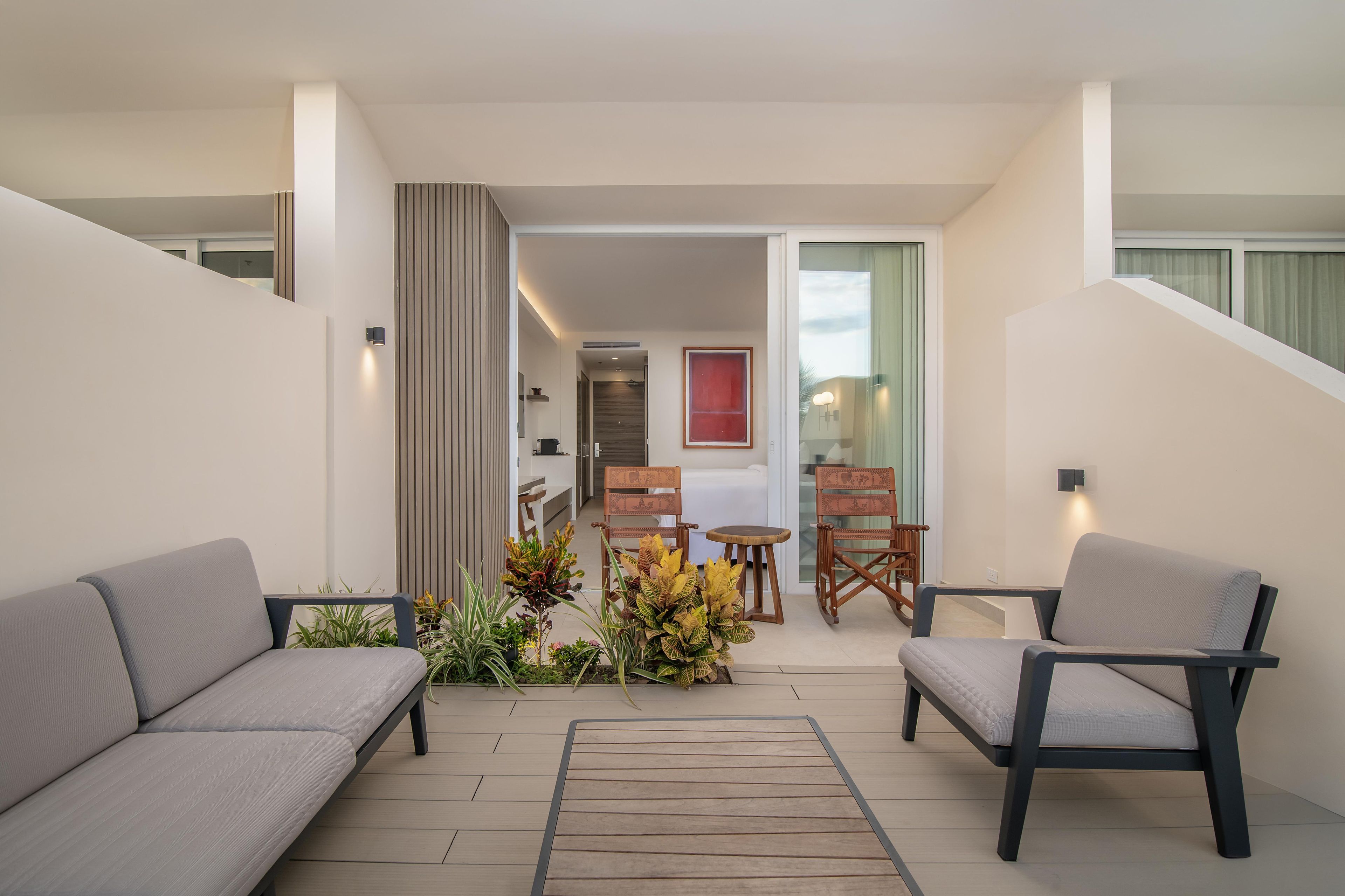 A modern interior with a sofa, chairs, a small table, and a plant arrangement.