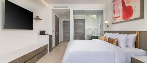 A modern hotel room with a large bed, a flat-screen TV, a bedside table, and a bathroom visible through an open door.