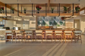Una cocina moderna con una isla central, taburetes de bar y plantas en macetas en el nivel superior.