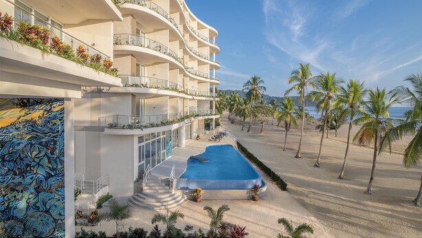Un hôtel doté d’une piscine, de plusieurs balcons et offrant une vue sur la plage.