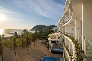 Un hôtel doté d’une piscine, offrant une vue sur la plage et disposant de balcons ornés de plantes.