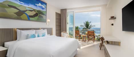 A hotel room with a large bed, a painting, a TV, and a balcony with chairs.