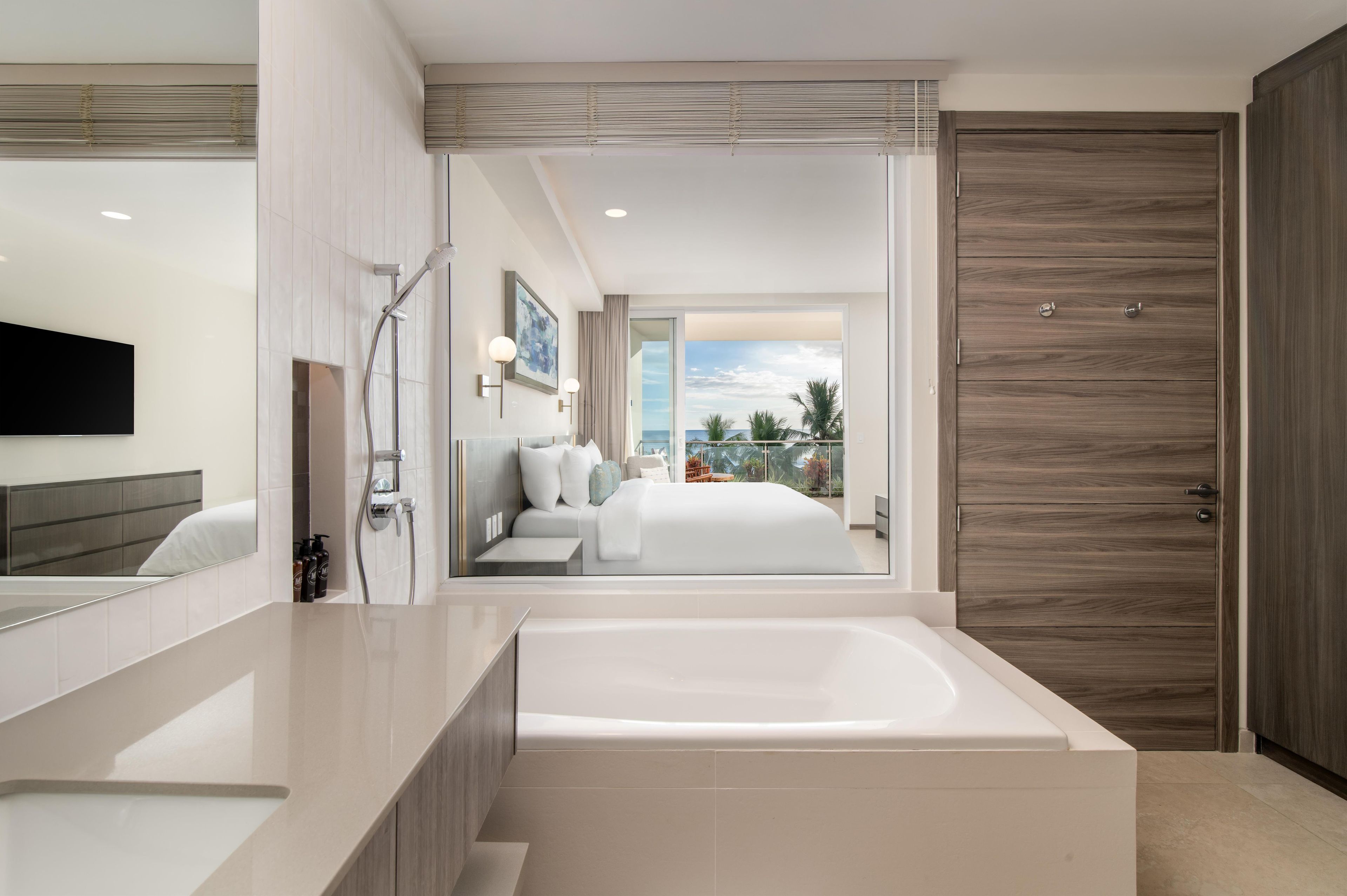 A modern bathroom with a bathtub, a shower, and a large mirror.