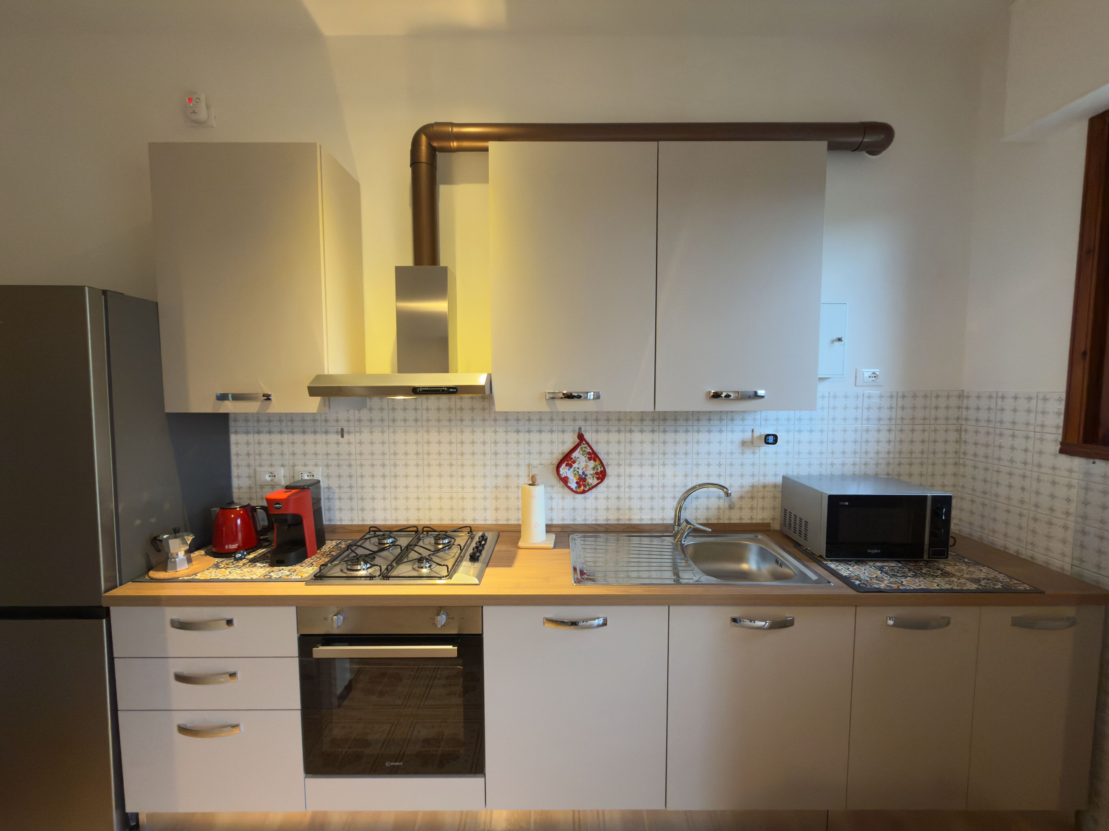 Et moderne køkken med hvide skabe, rustfrie stål-apparater og et mønstret bagpanel.