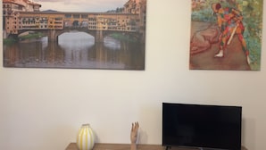 Two paintings on a wall, a vase, and a television on a wooden table. - Harmony Home Florence (Firenze)