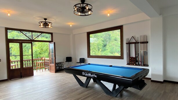A pool table in a room with large windows, a balcony, and a pool table set up for billiards. - Hospedaje Maria Elena (Pereira)