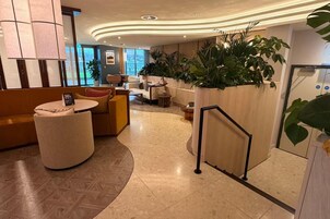 Un vestíbulo moderno con una zona de estar circular, una escalera y vistas al exterior.
