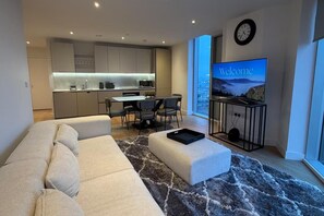 A modern living room with a sofa, ottoman, and a TV displaying "Welcome". - Modern City Apartment in Manchester (Manchester)