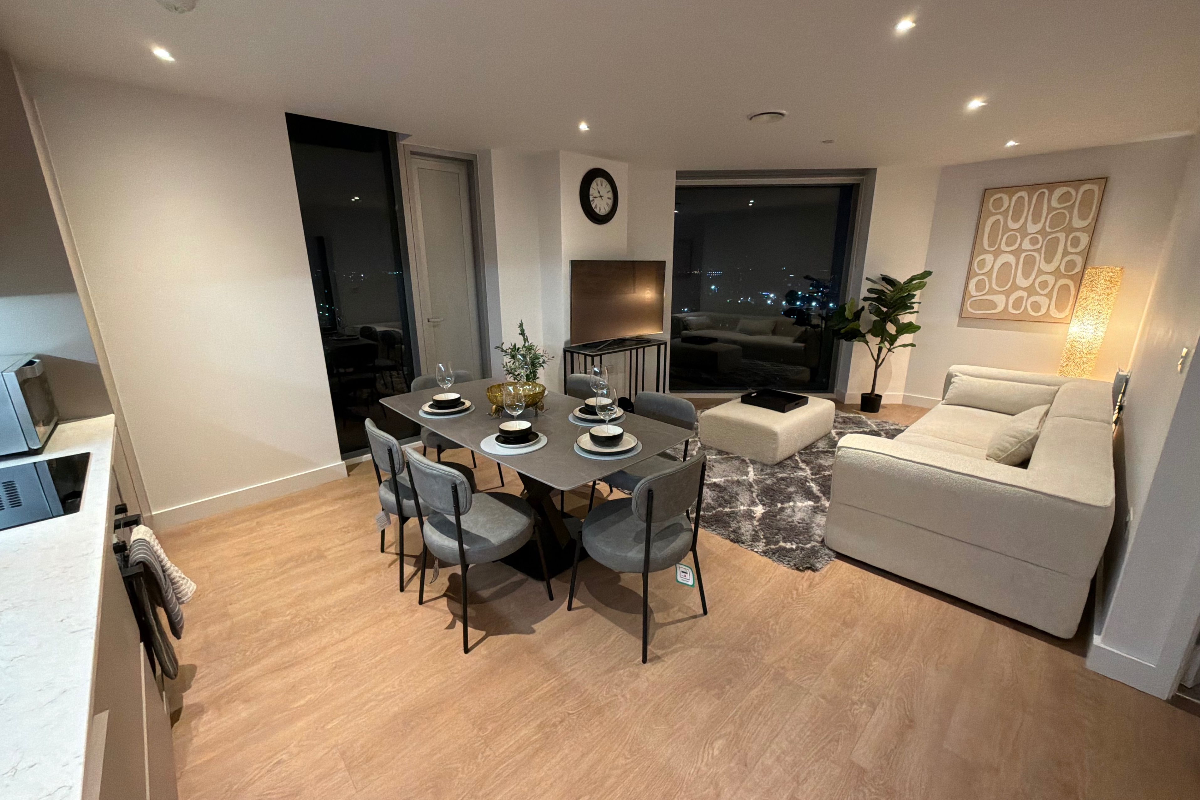 Una sala de estar moderna con comedor, un sofá, una mesa de centro y un ventanal con vistas a la ciudad.