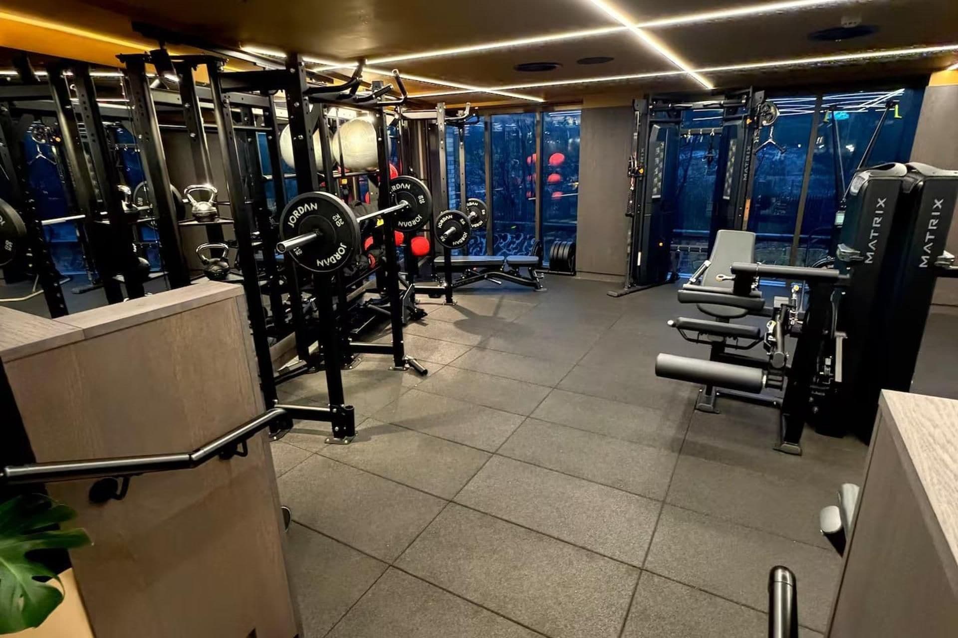 Een fitnessruimte met diverse trainingsapparaten, waaronder krachttoestellen en losse gewichten.