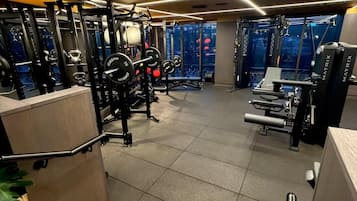 Een fitnessruimte met diverse trainingsapparaten, waaronder krachttoestellen en losse gewichten.