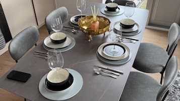 Een eettafel gedekt met borden, kommen, bestek en glazen, met een decoratieve schaal en een waterfles.