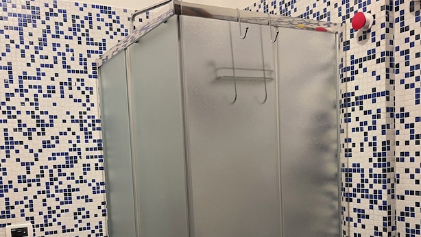 Une salle de bain avec un espace douche fermé, des murs carrelés et un rideau de douche.