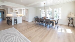 Una cocina amplia con una isla central, suelo de madera e iluminación colgante.