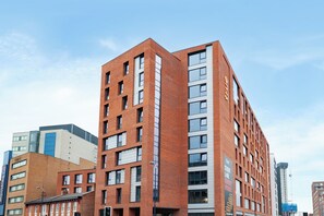 A multi-story building with a brick facade, large windows, and a sign indicating it is a student hostel. - Student Only True Birmingham  (Birmingham)