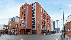 Een meerlaags gebouw met een opvallend bord dat aangeeft: 'echt studentenleven', wat aangeeft dat het studentenhuisvesting is.