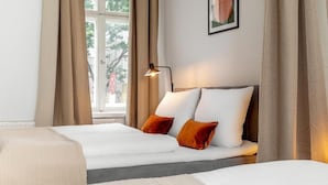 A hotel room with two beds, a window with curtains, a bedside lamp, and a framed picture on the wall. - Global Living Moritzplatz (Berlin)