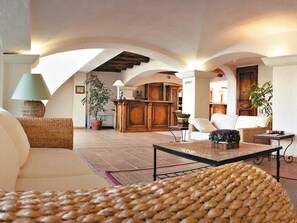 A spacious living area with a high ceiling, wooden furniture, and a central fireplace.
