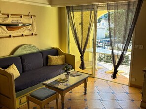 A living room with a sofa, a coffee table, and a view through a glass door.