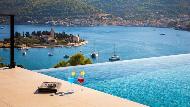 A poolside view overlooking a coastal town with boats, a church, and hills. - Breathtaking Villa Vis Five Bedroom Villa with the Pool (Vis)