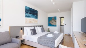 A modern bedroom with a bed, a grey sofa, and artwork on the walls. - Breathtaking Villa Vis Five Bedroom Villa with the Pool (Vis)