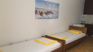A room with two single beds, a small kitchenette, and a painting of a lighthouse on the wall. - Apartments Aleksić, Bečići - Studio Apartment with Terrace 2 (Becici)