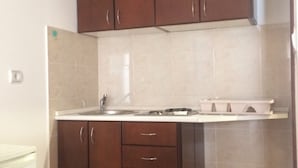 A kitchen with brown cabinets, a white countertop, and a stainless steel sink. - Apartments Aleksić, Bečići - Studio Apartment with Terrace 2 (Becici)