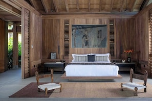 Une chambre spacieuse avec un grand lit, des murs en bois et un tableau accroché au-dessus du lit.