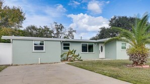 A single-story building with a front door, a small porch, and a concrete driveway. - The Angler's Dream- Beautiful 4BR Home & HUGE Pool (Clewiston)