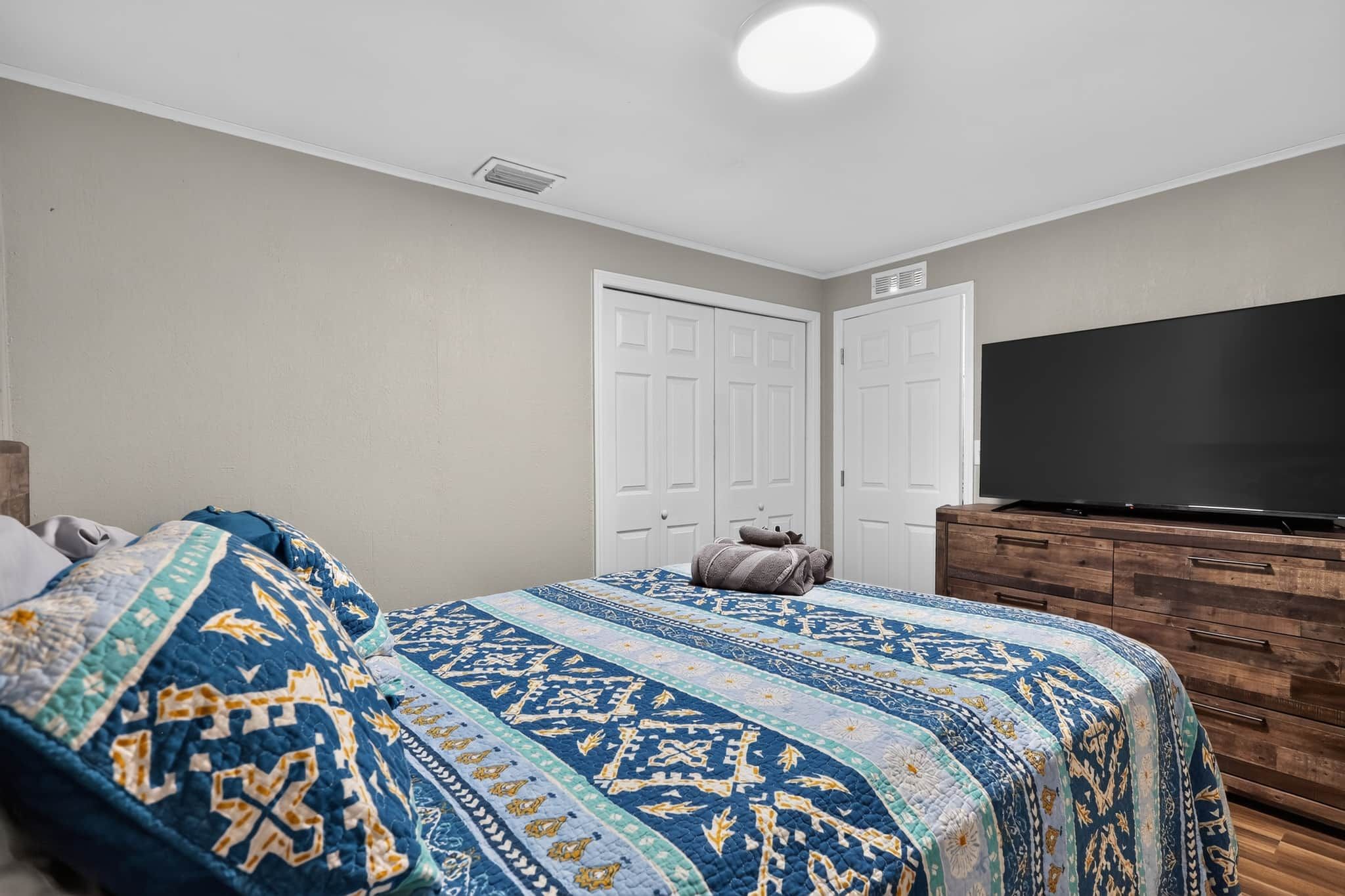 Un dormitorio con cama, televisión, armario y puerta.