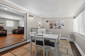 Una sala de estar moderna con comedor, chimenea y un ventanal con persianas.