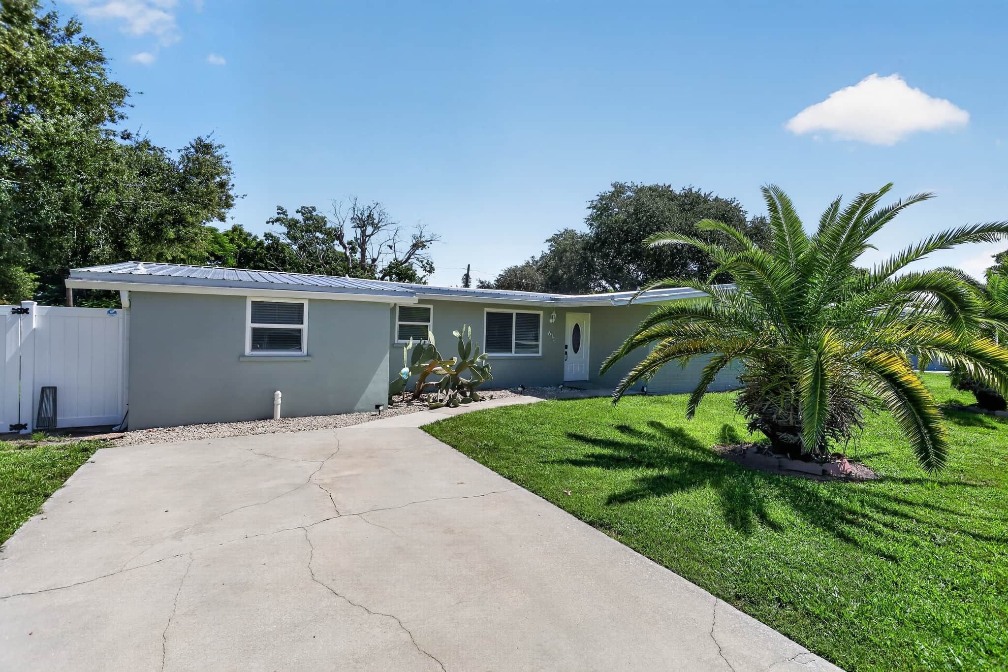 A single-story house with a concrete driveway leading to a front door.