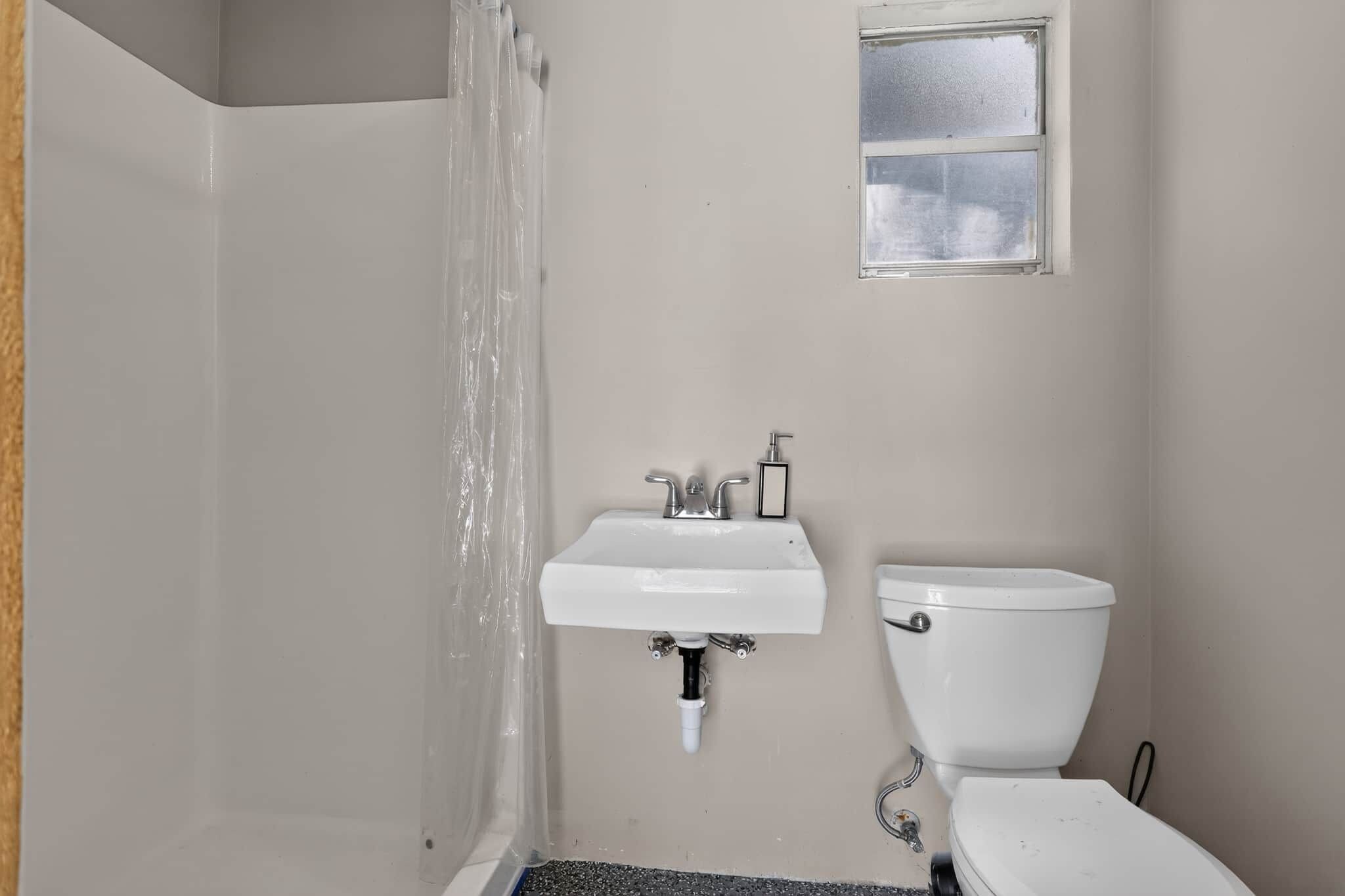 A bathroom with a shower, sink, and toilet.