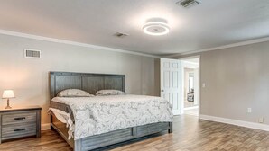 A bedroom with a bed, nightstand, and lamp. - The Angler's Dream- Beautiful 4BR Home & HUGE Pool (Clewiston)