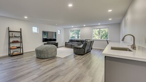 A modern living room with a grey sofa, ottoman, and bookshelf. - Stylish Everett Home w/ Green Belt! (Everett)