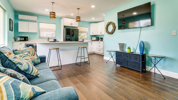 A modern kitchen with white cabinets, a stainless steel refrigerator, and a flat-screen TV mounted on the wall. - Beach Days & Backyard Nights! Fort Myers Retreat (Fort Myers)